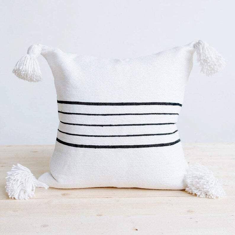 Coussin artisanal blanc à pompons et rayures noires