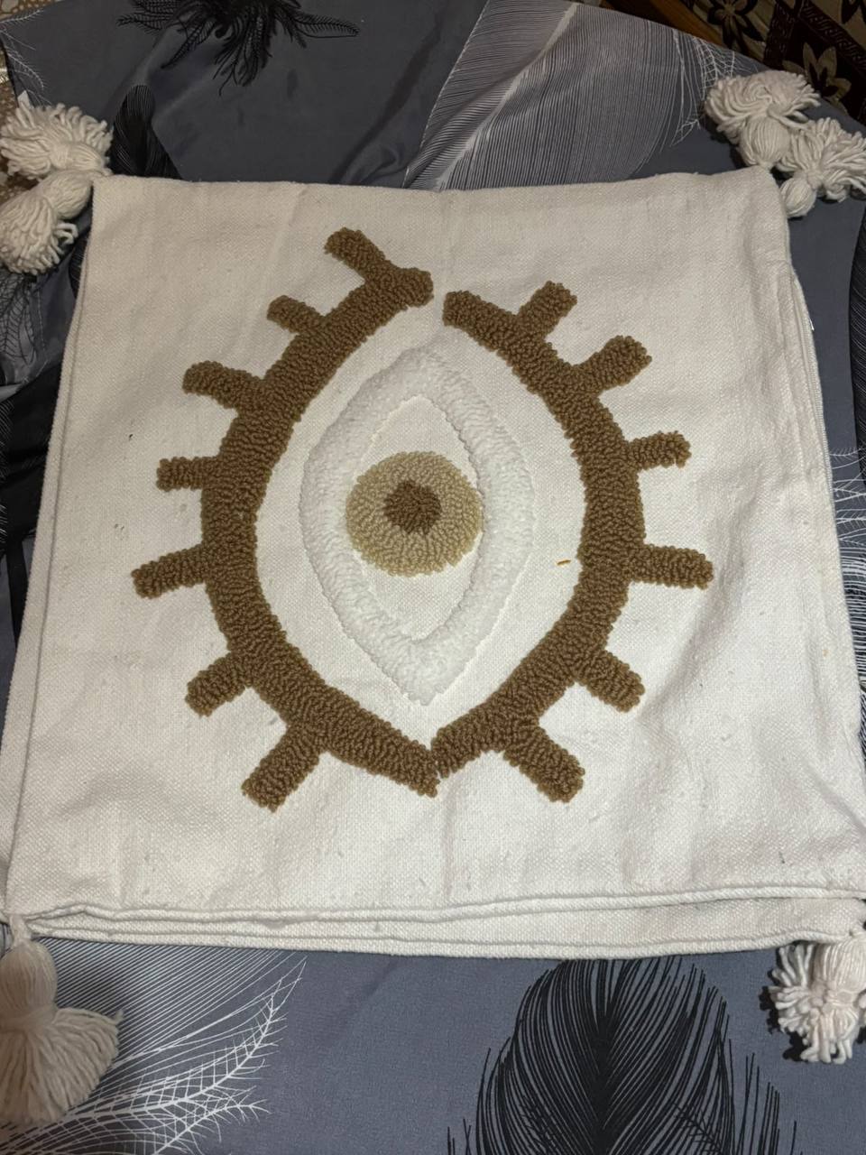 Coussin artisanal œil punch needle avec pompons