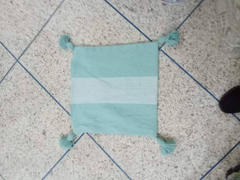 Coussin artisanal à pompons turquoise